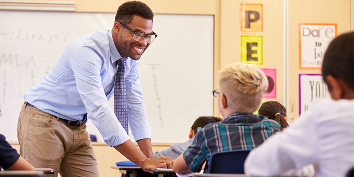 Teacher bending down to help student at a desk