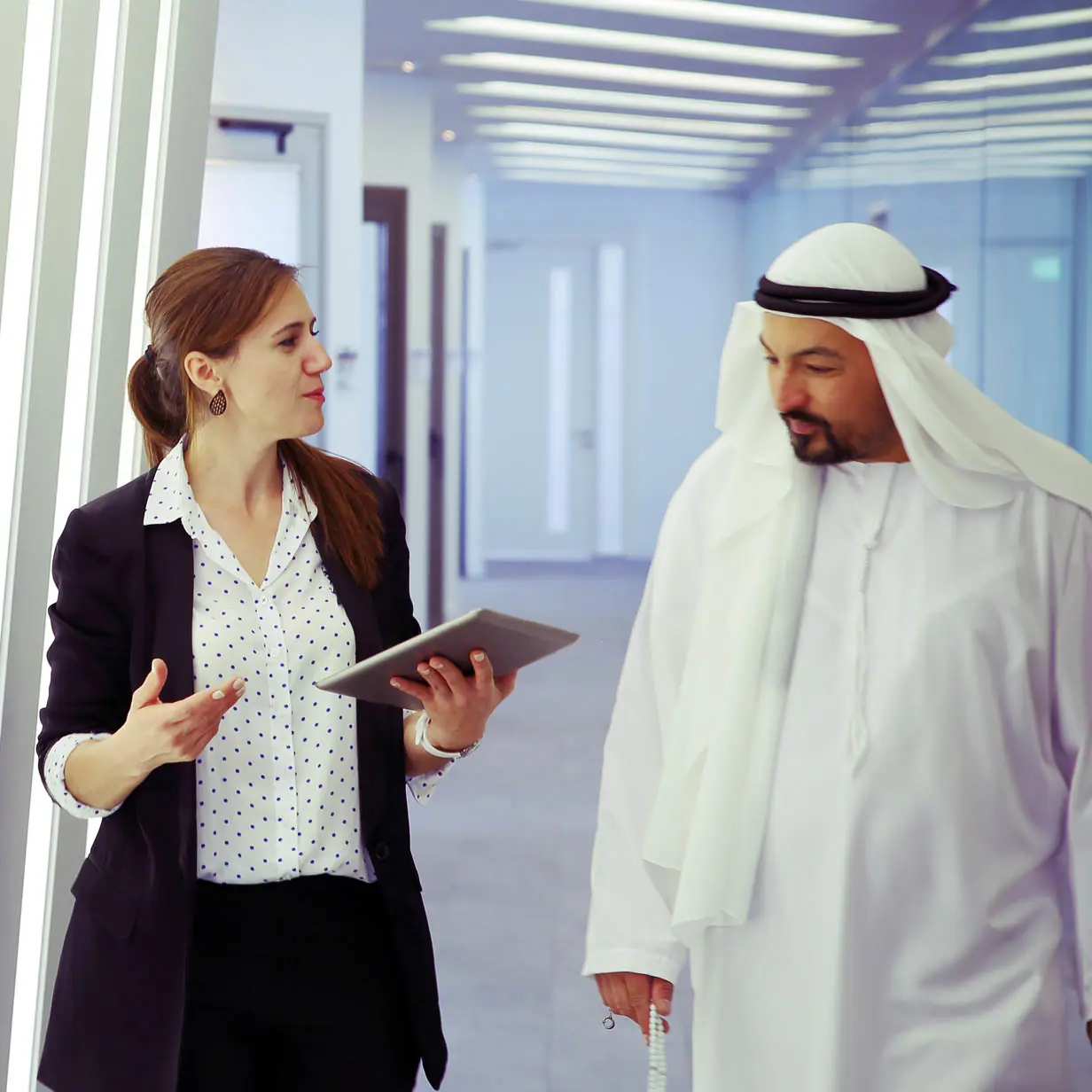 A man and woman walking and talking together in a business setting. 