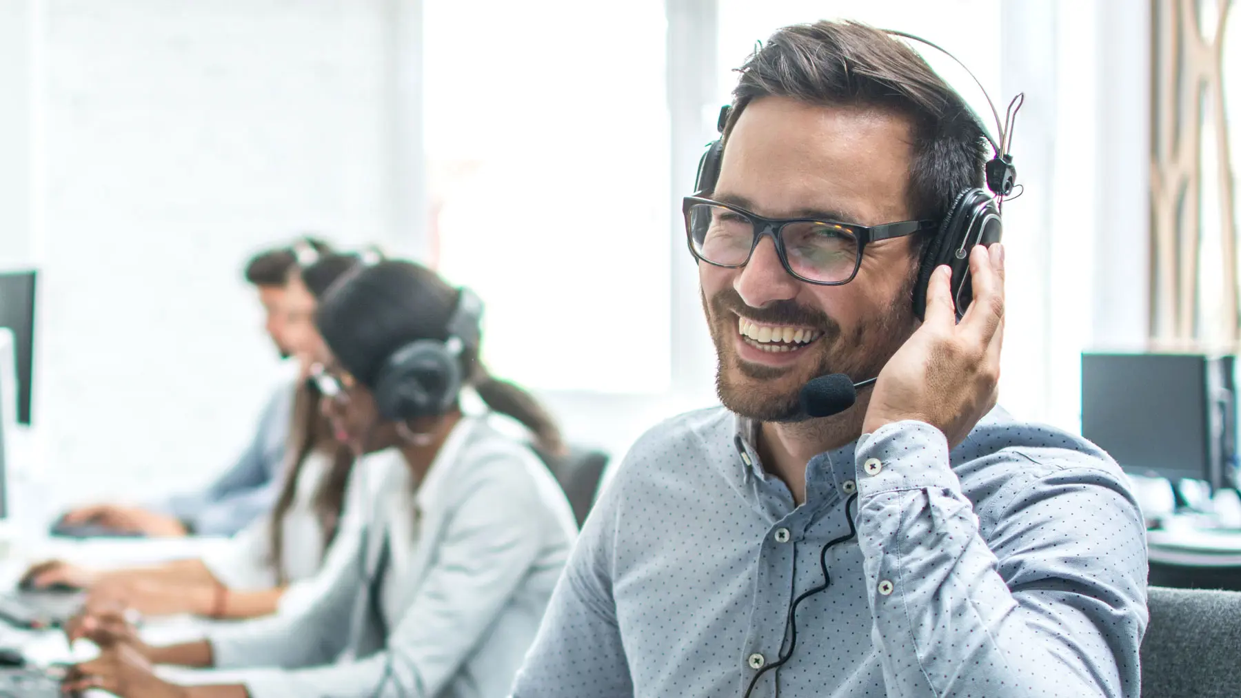 A man in a customer service department, smiling and giving advice while talking on the phone.