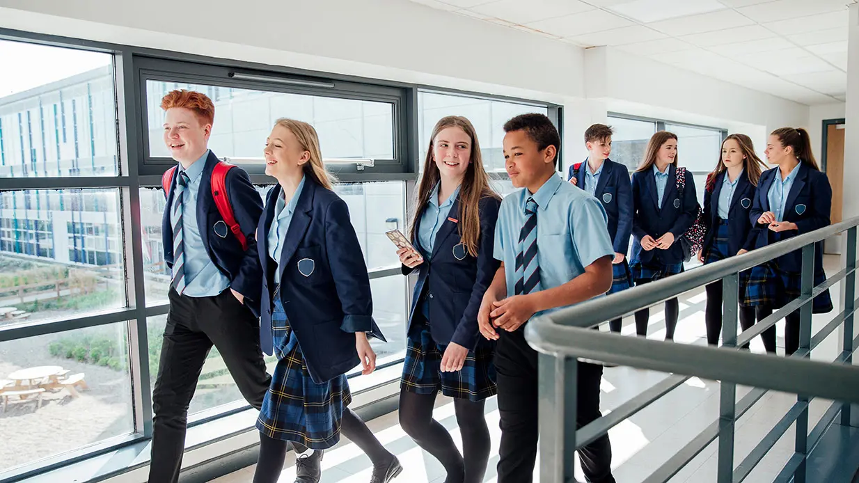 A group of students walking down hallway.