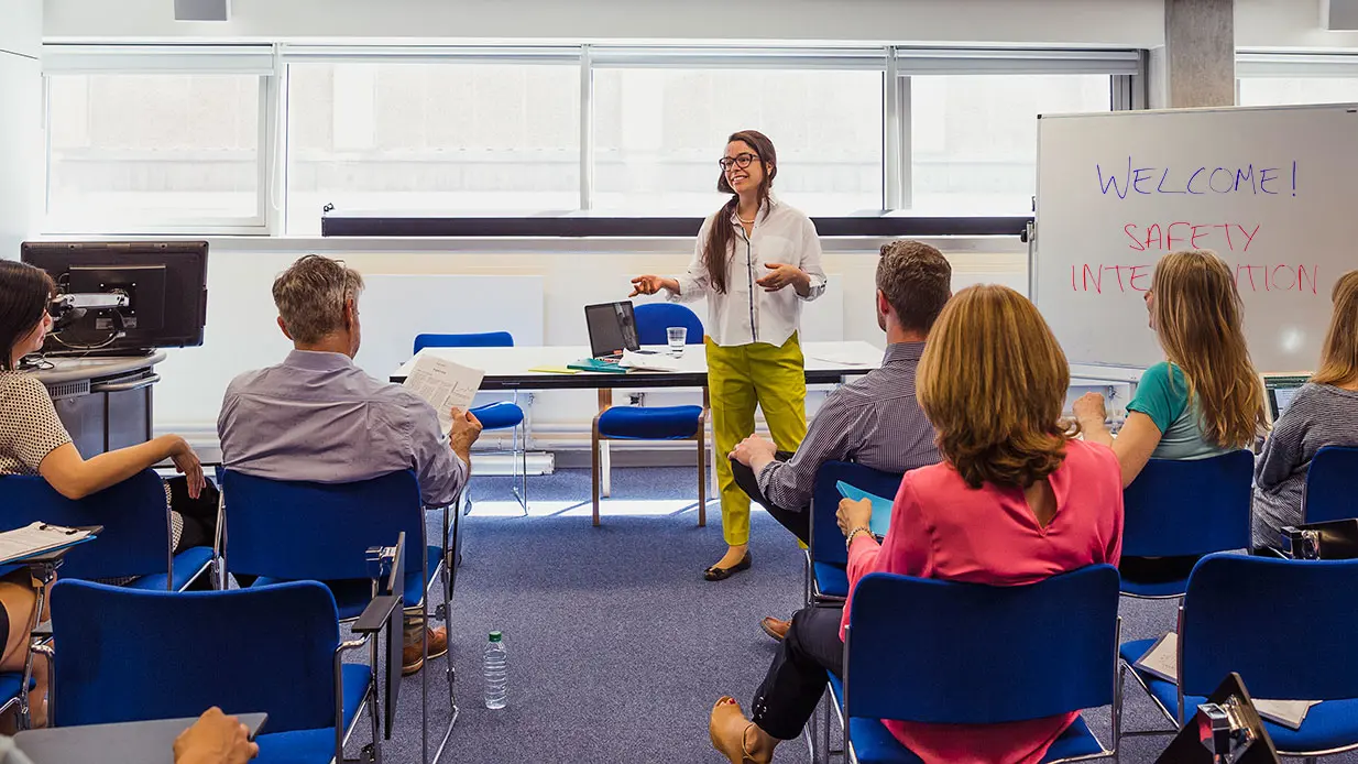 A CPI trainer stands at the front of the room with "Welcome! Safety Intervention" written on it. 