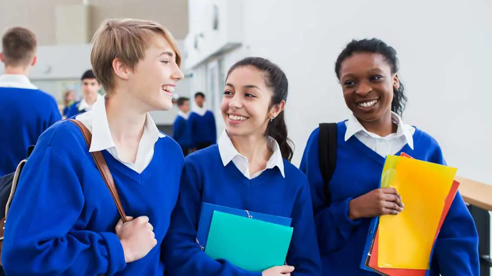 Three students smiling in a school hallway