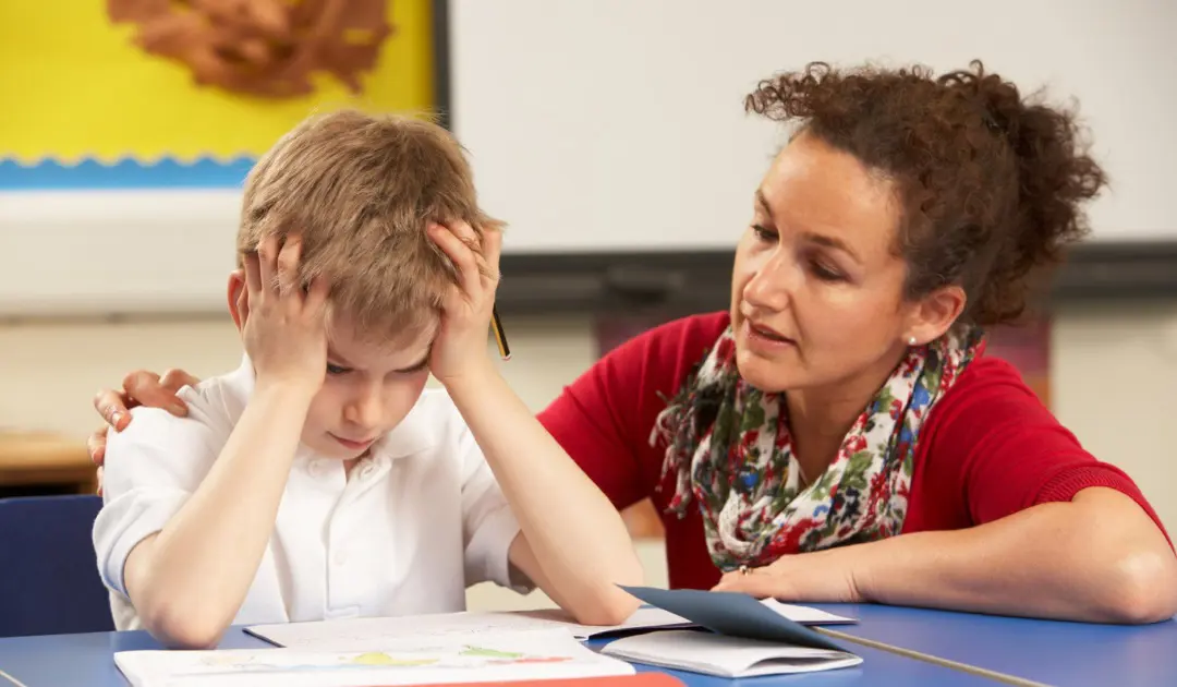 School teacher comforting a student at a desk